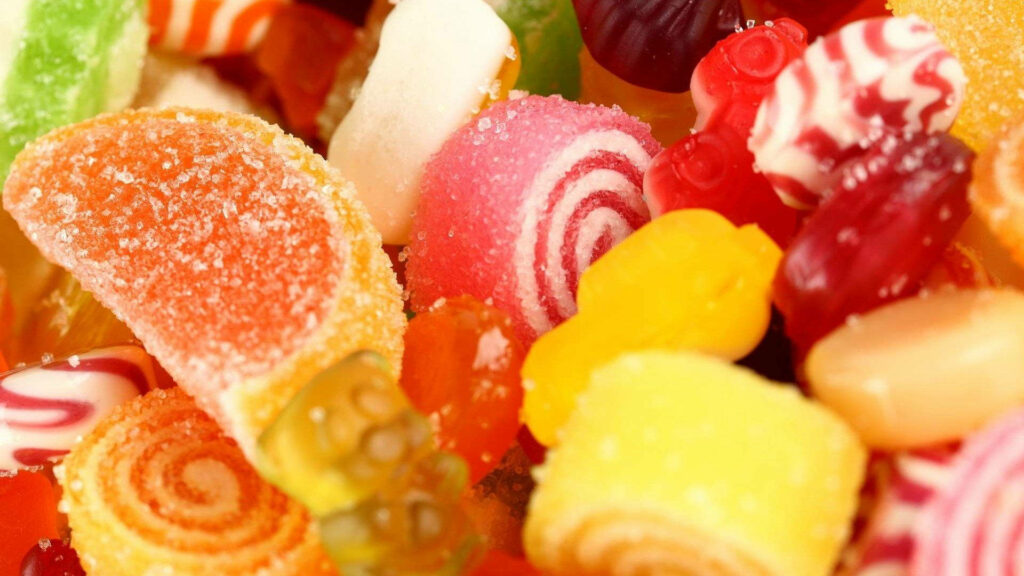Close-up of vibrant sugar-coated gummies jelly candies and fruit slices in bright colors wallpaper