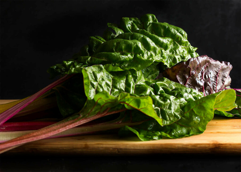Colorful Swiss Chard Wallpaper: Fresh Greens & Reds on Wooden Board