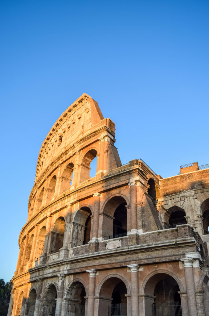 Ancient Colosseum ruins in warm sunlight with clear blue sky detailed Roman arches wallpaper