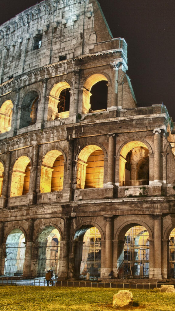 Colosseum at night illuminated with warm lights showing ancient Rome architecture wallpaper