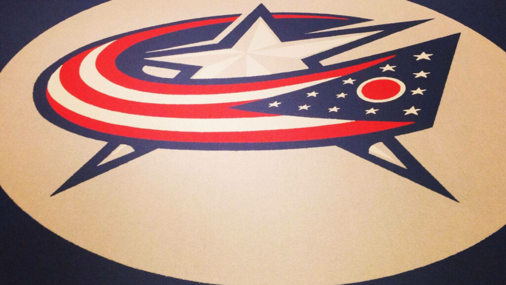 Columbus Blue Jackets logo on textured floor with patriotic red white and blue star flag design wallpaper