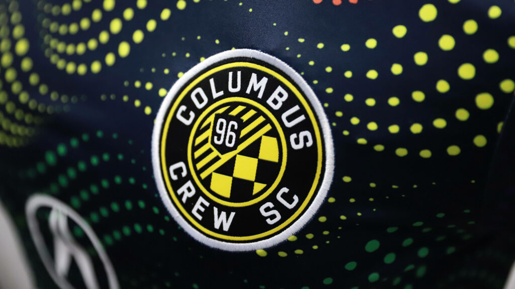 Columbus Crew logo with yellow dot rays on dark geometric background black and yellow wallpaper