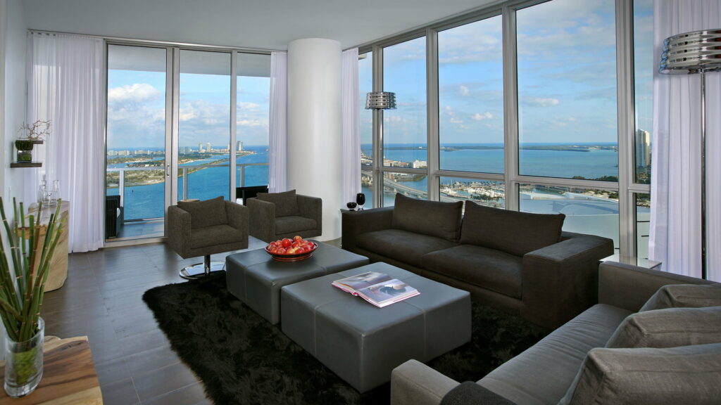 Modern luxury living room with charcoal furniture leather ottomans and coastal city skyline view Wallpaper