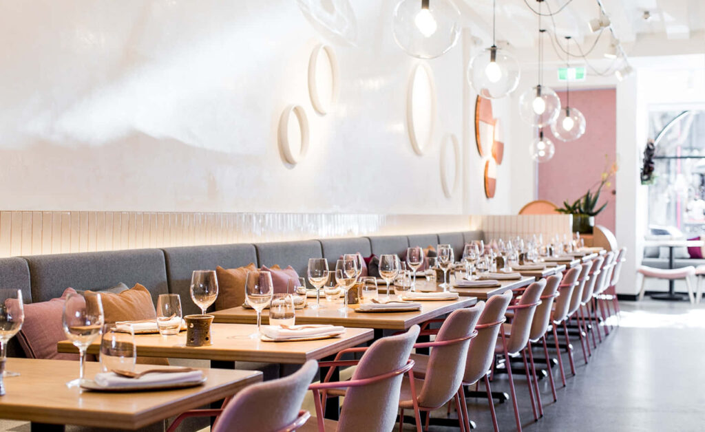 Communal Dining at a Chic Restaurant: Long Table and Chairs Against a Stunning Background Wallpaper