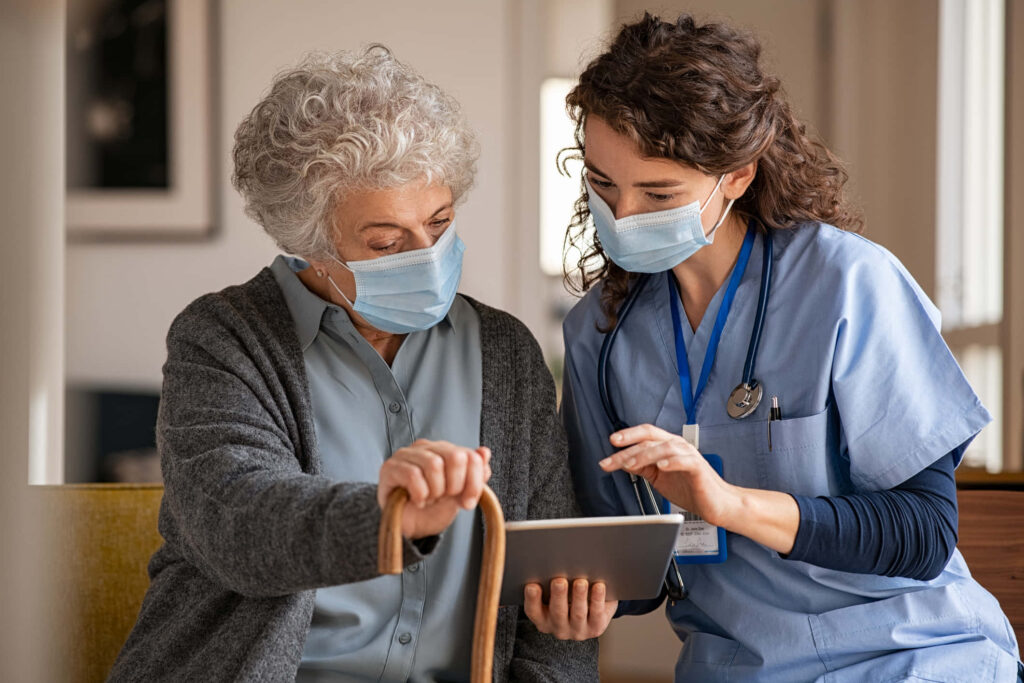 Compassionate doctor in blue scrubs helping elderly woman in calm healthcare setting wallpaper