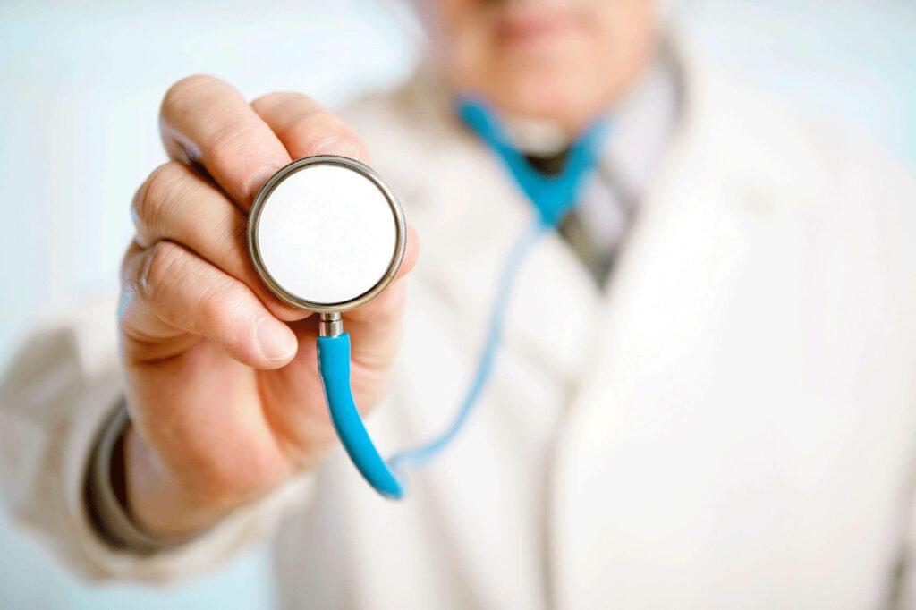Doctor in white coat holding blue stethoscope closeup symbolizing healthcare and trust wallpaper