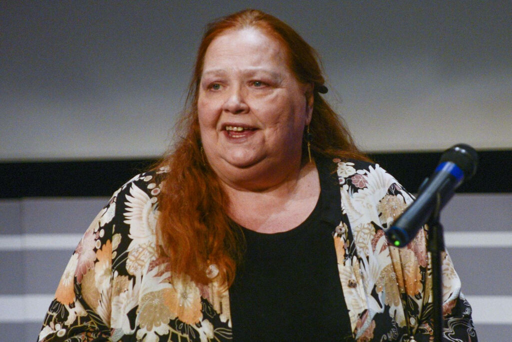 Conchata Ferrell speaking at charity event wearing floral kimono jacket with red hair flowing Wallpaper