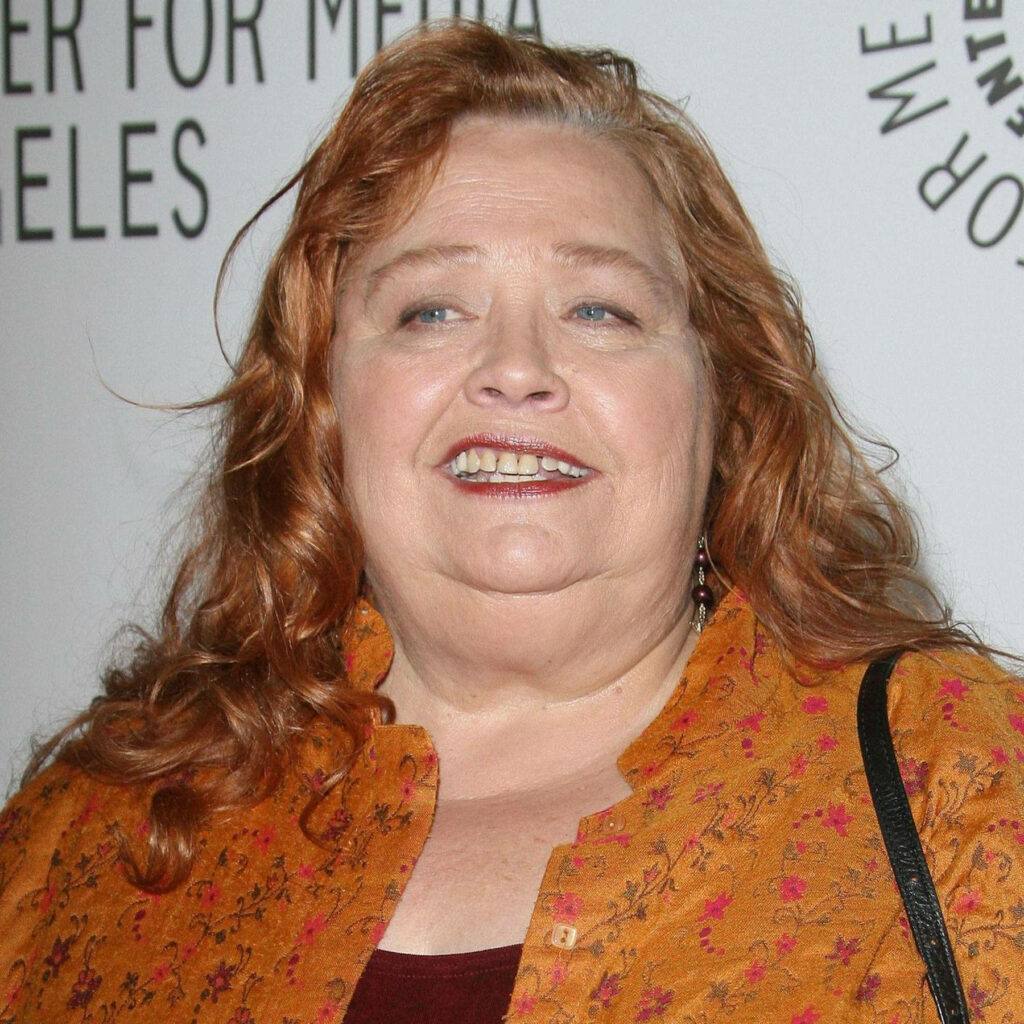 Conchata Ferrell at The Paley Center event wearing rust jacket with auburn hair and logo backdrop Wallpaper