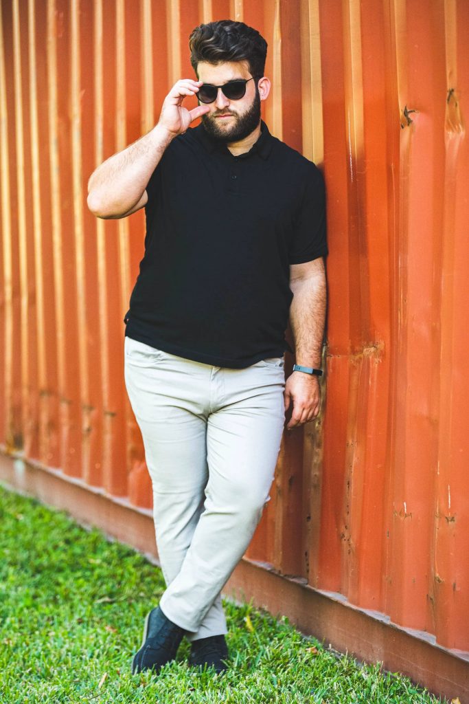 Plus-sized bearded man in sunglasses and black polo by orange rusty container wallpaper background