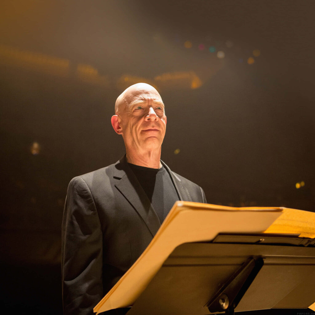 Confident Conductor at Podium: Warm Lighting Wallpaper Background