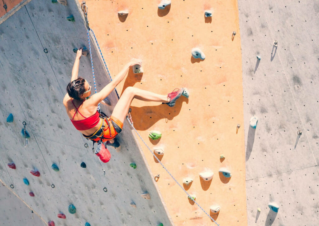 Young woman confidently climbing indoor wall showing strength and determination in sport climbing Wallpaper