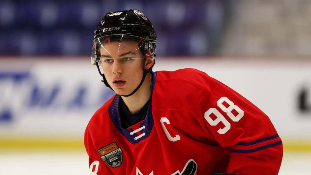 Connor Bedard red jersey helmet intense focus hockey prospect ice arena blurred background wallpaper