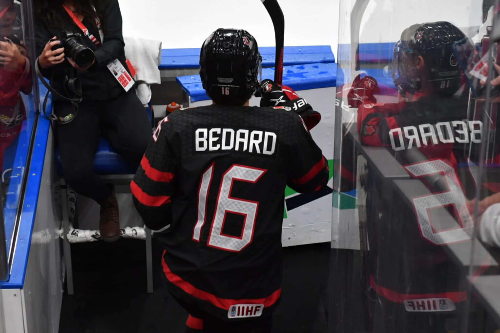 Connor Bedard in black red Team Canada hockey jersey number 16 reflection on rink glass wallpaper