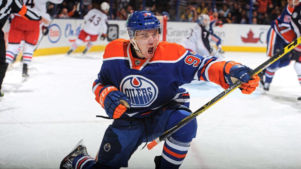 Connor McDavid Edmonton Oilers celebrating on ice vibrant blue orange NHL action wallpaper background