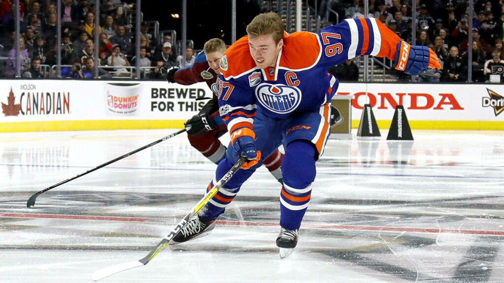 Connor McDavid Edmonton Oilers number 97 in blue orange uniform skating fast on ice hockey wallpaper