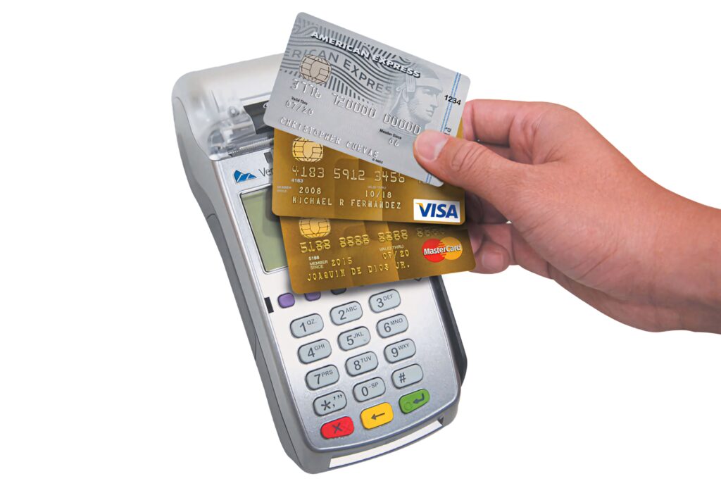Person holding sleek gold credit card over modern payment terminal demonstrating contactless payment technology Wallpaper