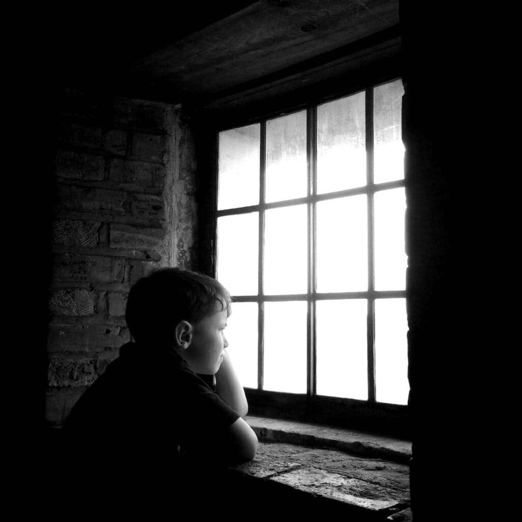 Contemplative Child by Window: Nostalgic Black & White Wallpaper Background