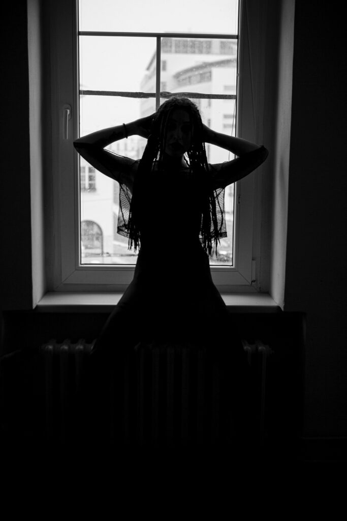 Silhouette of Contemplative Girl with Dreadlocks by Window Wallpaper