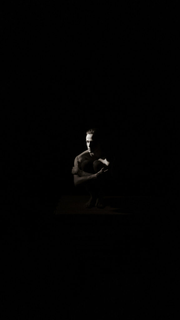 Contemplative Man in Shadows: Ominous Atmosphere in Dim Light Wallpaper