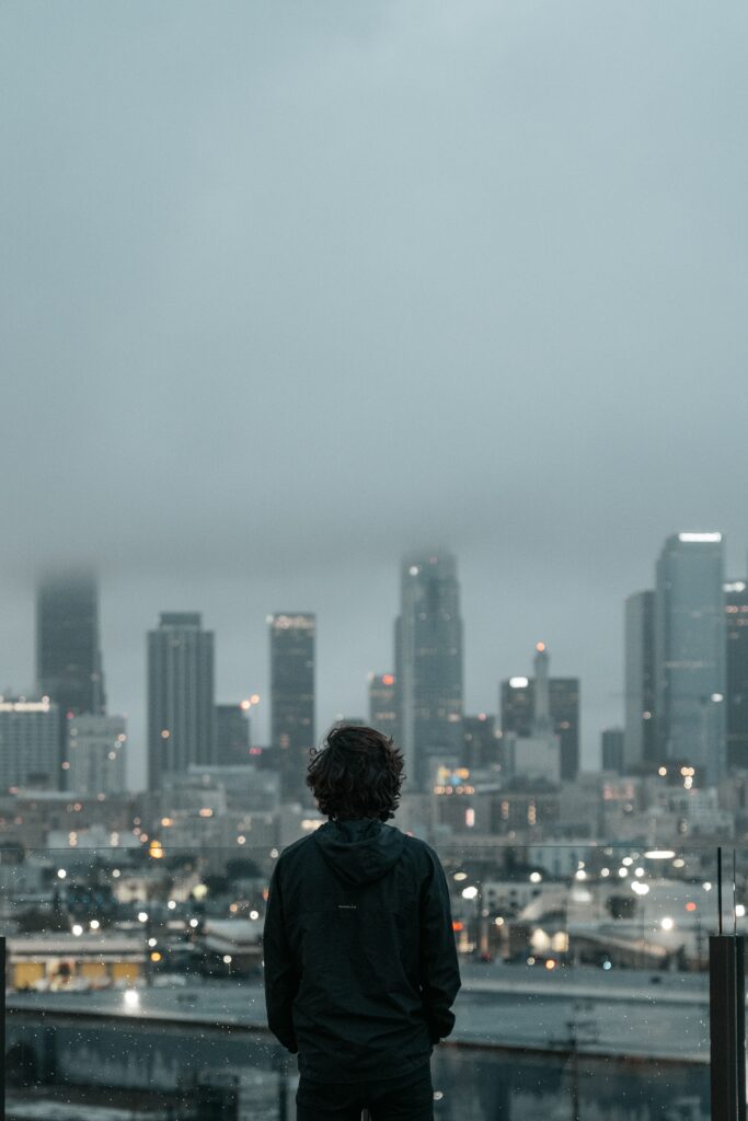 Serene Rooftop View: Contemplative Man Overlooks Misty Cityscape Wallpaper