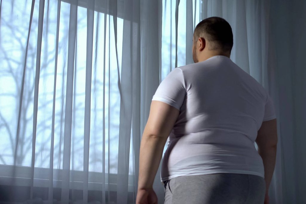 Plus-size man in sunlit room with white curtains reflecting quietly in digital wallpaper background