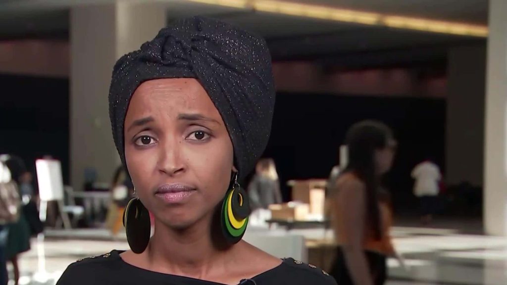 Portrait of U.S. Representative Ilhan Omar in black sparkling headwrap and colorful earrings Wallpaper