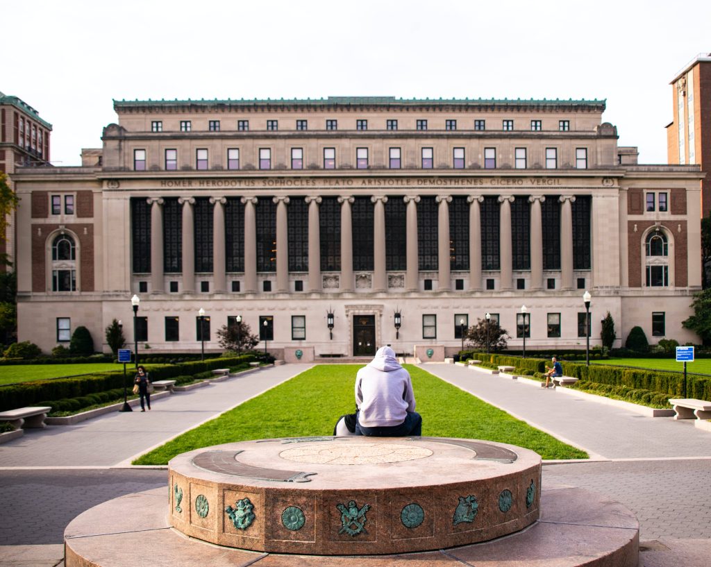 Contemplative student in grey hoodie at Columbia University Butler Library neoclassical facade Wallpaper