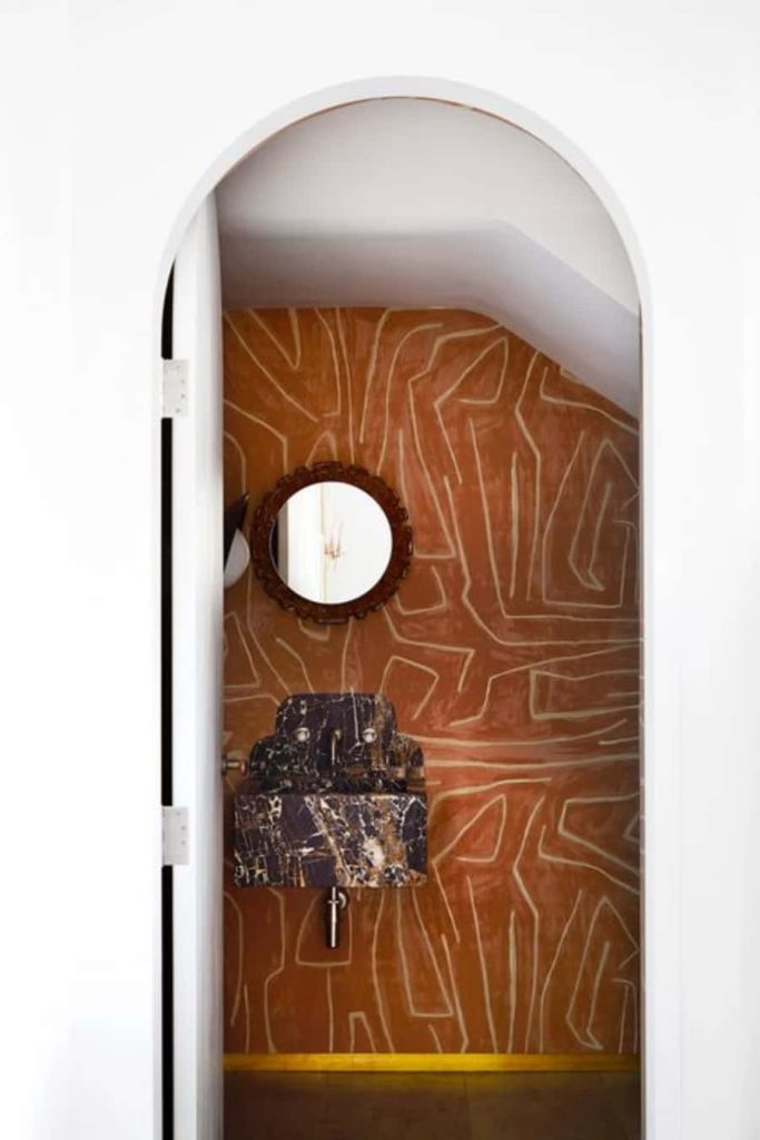 Contemporary powder room with terracotta walls abstract art black marble sink and round mirror Wallpaper
