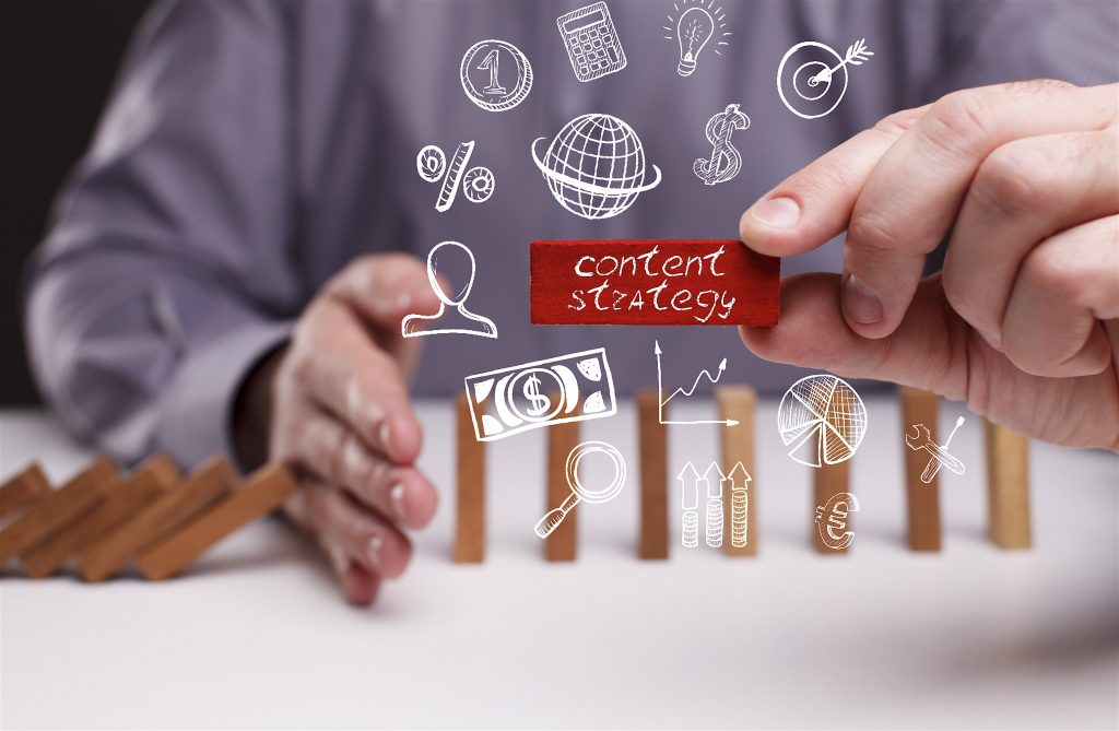 Hand holding red content strategy block above falling wooden dominoes with business icons Wallpaper