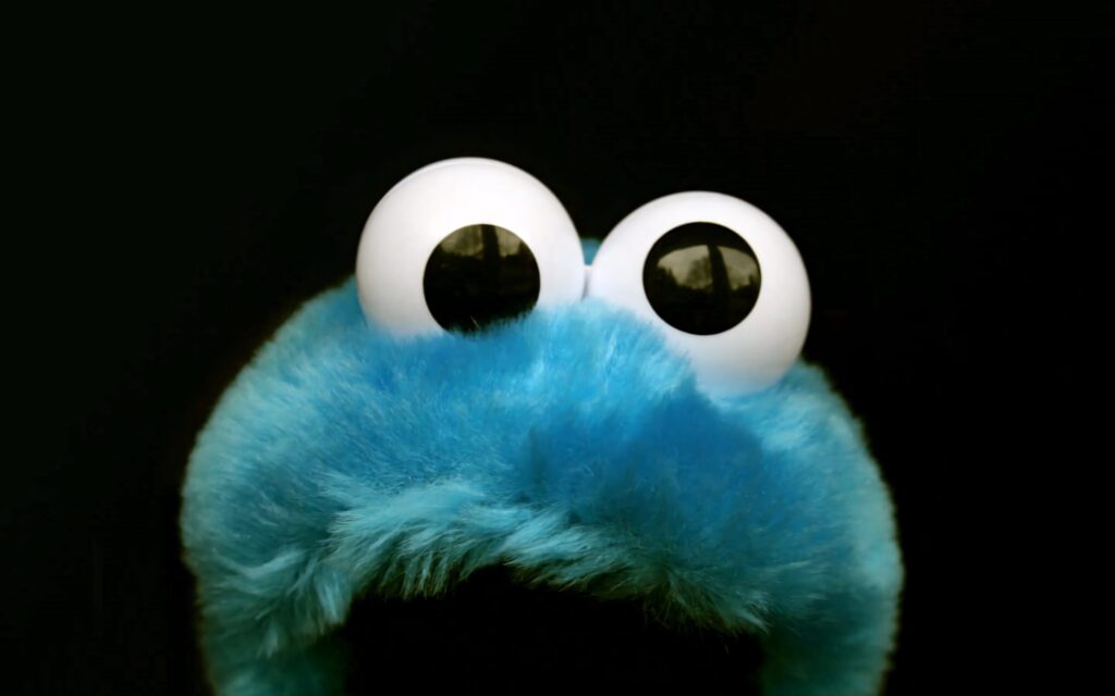 Close-up Cookie Monster with googly eyes and blue fur on black background Sesame Street wallpaper