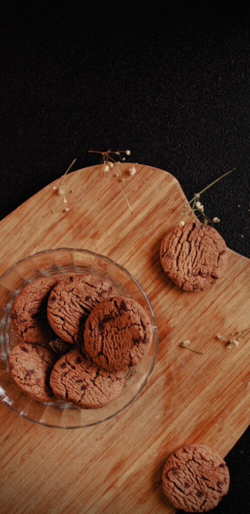 Cookies Galore: A Flat-lay Composition with Delicious Treats on a Stylish Wooden Board Against a Sleek Black Backdrop Wallpaper