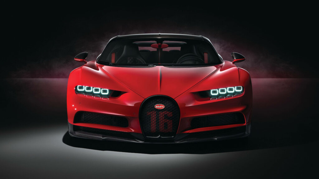 Roaring Beauty: A Captivating Shot of a Red Bugatti Chiron Super Sport Car Amidst Smoky Ambiance, Resting Gracefully on a Sleek Concrete Canvas Wallpaper