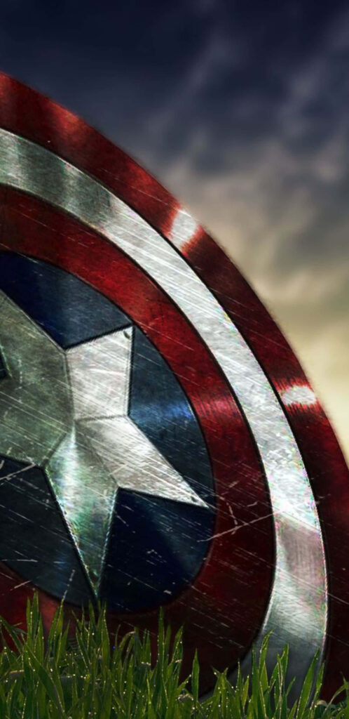 Battle-Scarred Shield: A Cool Captain America Tribute on Verdant Grounds Wallpaper