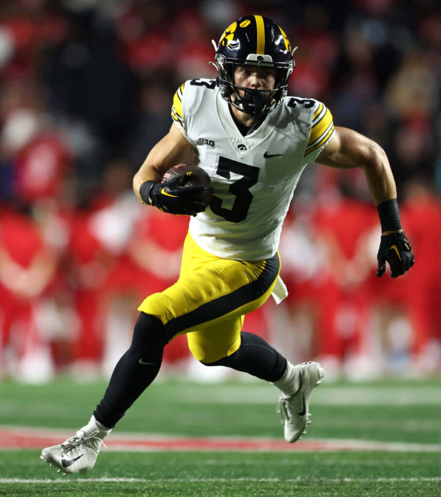 Cooper DeJean in Iowa Hawkeyes uniform showcasing intense focus and speed on football field Wallpaper
