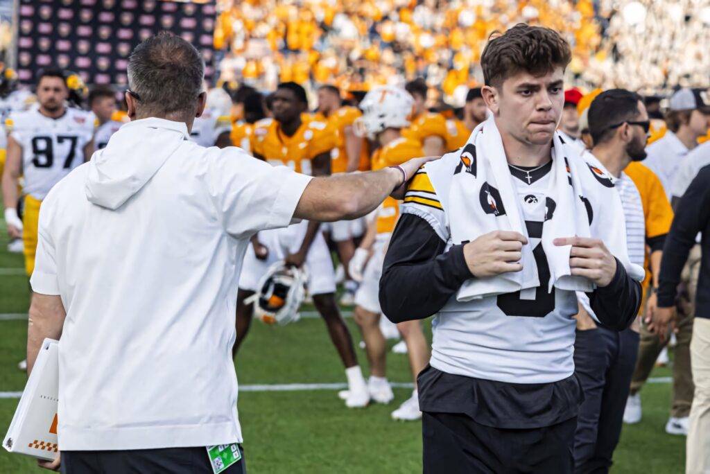 Cooper DeJean in Iowa Hawkeyes uniform on football field showing focus and determination Wallpaper