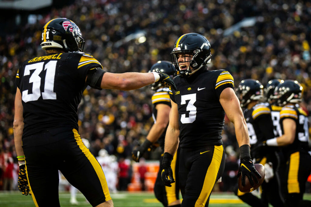 Cooper DeJean Iowa Hawkeyes football player in black and gold uniform on vibrant stadium field Wallpaper