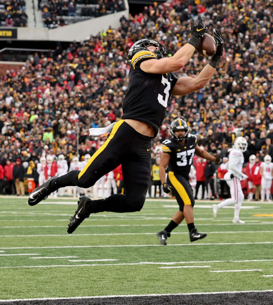 Cooper DeJean leaps in midair catching football in black and gold Iowa Hawkeyes uniform on field Wallpaper