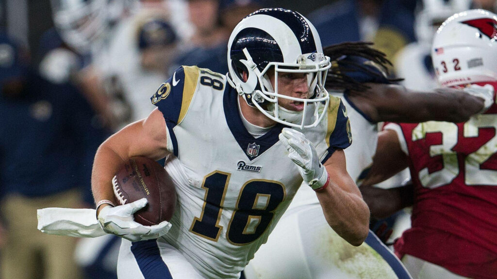 Cooper Kupp running with football in Los Angeles Rams uniform during intense NFL game action Wallpaper