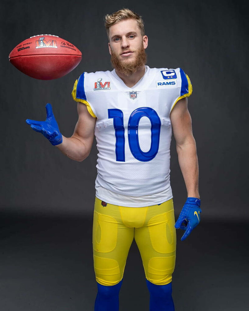 Cooper Kupp in Los Angeles Rams uniform tossing football in NFL photoshoot with wallpaper background