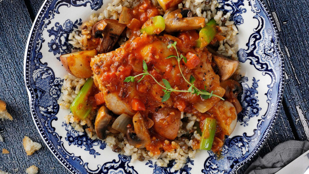 Elegant Coq au Vin over Rice on Blue-Patterned Dish - Rustic Wallpaper