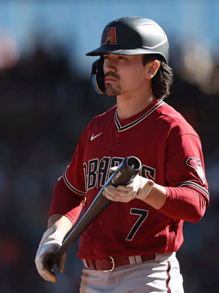 Corbin Carroll in Arizona Diamondbacks uniform ready to bat on sunlit baseball field background Wallpaper