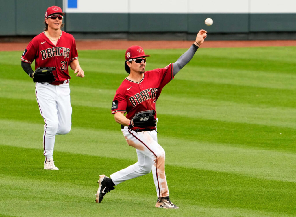 Corbin Carroll mid-throw in Arizona Diamondbacks uniform on vibrant green outfield grass MLB action Wallpaper