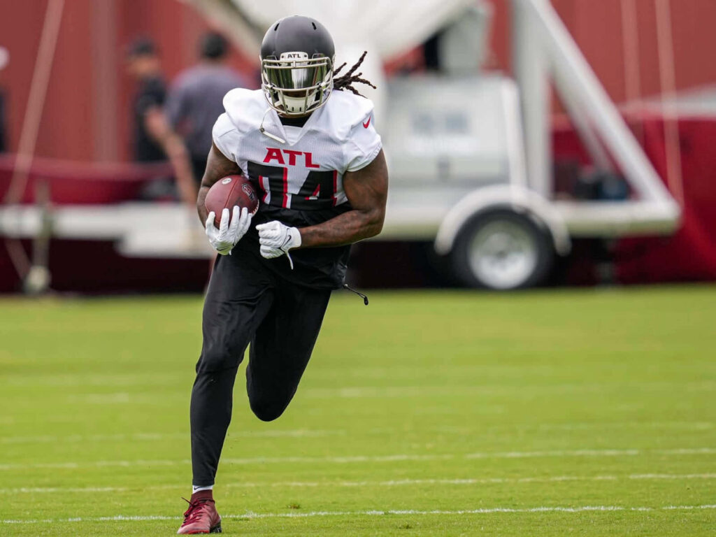 Cordarrelle Patterson Atlanta Falcons training action dynamic movement on vibrant green field Wallpaper