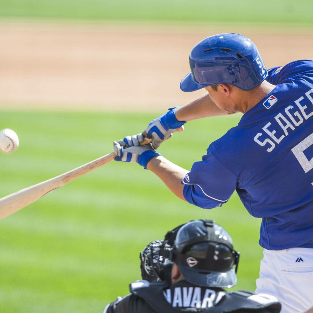 Corey Seager swings bat hitting baseball in vivid blue white uniform under bright sunlight Wallpaper