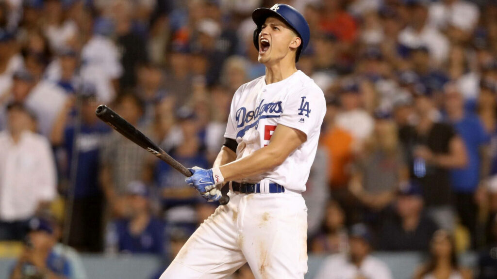 Corey Seager cheering with bat in Dodgers uniform against a vibrant stadium and crowd background Wallpaper
