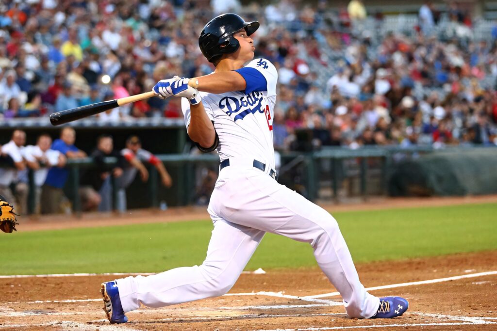 Corey Seager mid-swing in Los Angeles Dodgers uniform on vibrant green field with stadium crowd Wallpaper