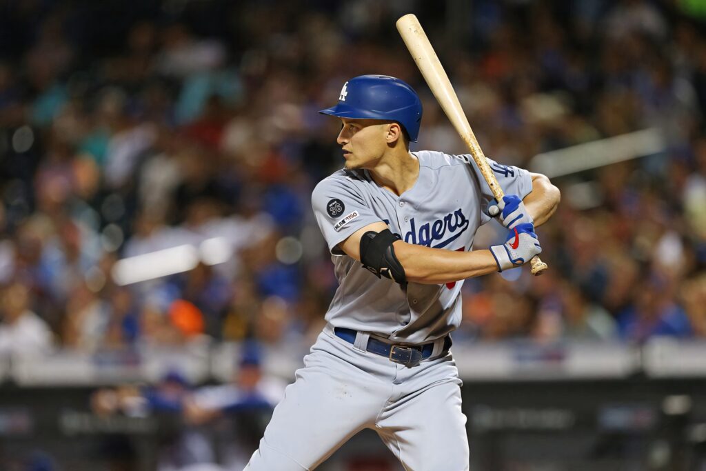 Corey Seager poised to swing in Dodgers uniform under stadium lights with blurred crowd background Wallpaper