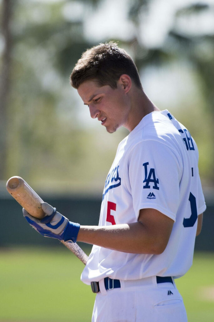Corey Seager in Los Angeles Dodgers uniform focusing on baseball bat with green field background Wallpaper
