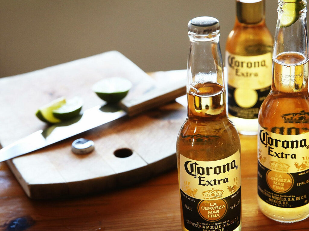 Corona Extra bottles on rustic table with fresh lime wedges vintage Mexican summer vibe wallpaper