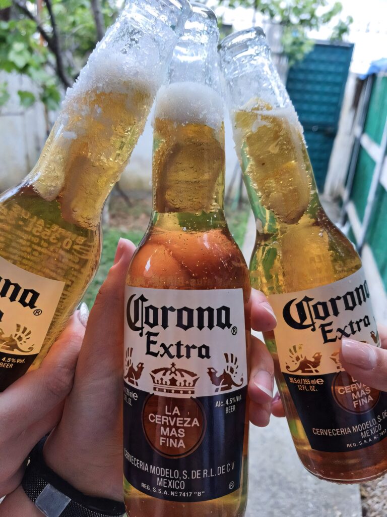 Three hands toasting with cold Corona Extra beer bottles in a sunny outdoor celebration background Wallpaper